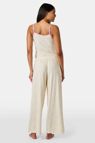 A yellow Mini Monkey Blossom Clarkson Cami by Roller Rabbit, featuring spaghetti straps, a small floral print, and purple trim along the neckline and straps, displayed on a plain white background. This camisole pairs perfectly with the Monroe Lounge Pant for a coordinated look.