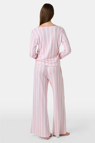 A woman smiles while wearing the Roller Rabbit Daisy Heart Stripe Jessie Long Sleeve Tee, a soft Pima cotton top adorned with pink and red daisies, paired with matching pajama bottoms, against a plain white background.