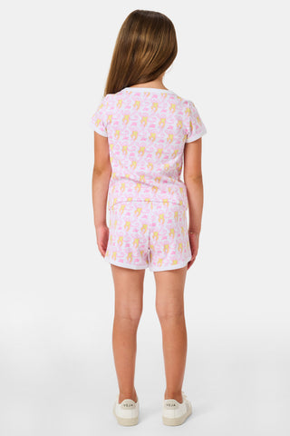 A young girl with long brown hair wears the Roller Rabbit Kids Monkey Playa Play Set and white shoes, standing and smiling against a plain white background.