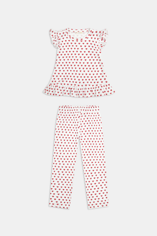 A child with long blonde hair wears the Roller Rabbit Kids Hearts Riley Set made from Pima Waffle fabric, featuring red hearts and ruffled cap sleeves, while holding a notebook with a decorative cover and standing in front of lockers.