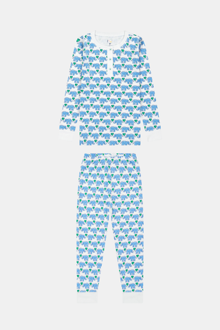 A young girl smiles in Roller Rabbit Kids Hathi Hearts Pajamas with long sleeves and a colorful animal print. She has long brown hair, is barefoot, and stands against a plain white background.