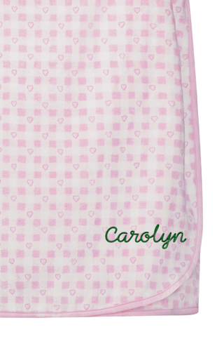 The Roller Rabbit Gingham Hearts Spa Headband is crafted from 100 cotton terrycloth and showcases a pink and white checkered pattern accented with small hearts. It features a convenient hook-and-loop fastener and is displayed laid flat on a white background.