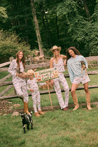 Meet the Saddle Up Pajamas by Roller Rabbit: a long-sleeved Pima cotton set on a white background, adorned with vibrant animal and tree motifs. The top features buttons at the neckline, while the elastic-waist pants offer comfy ease—ideal for horse girls who appreciate playful patterns and cozy comfort.