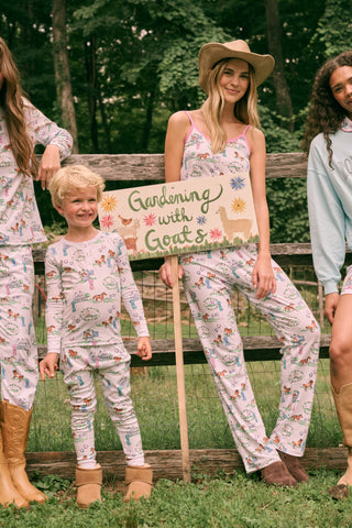 Introducing the Kids Saddle Up Pajamas by Roller Rabbit—a children’s pajama set crafted from premium Pima cotton, featuring a whimsical equestrian print of horses, castles, and greenery on a white background. This high-quality set includes a long-sleeve top and matching pants.