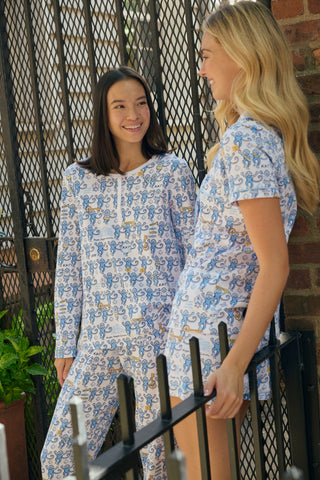 The Roller Rabbit Kappa Kappa Gamma Monkey Pajamas are a two-piece set with long sleeves and pants, showcasing an all-over blue and yellow monkey cartoon print on a white background, displayed on a flat white backdrop.