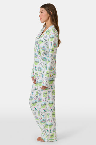 Introducing the Game, Set, Monkey Long Sleeve Polo Pajamas by Roller Rabbit—a cozy white pajama set expertly crafted from soft Pima Cotton. The set features a playful Game Set Monkey print with vibrant green, blue, and yellow animal and nature illustrations. Designed with long sleeves, a button-up polo top, and comfortable drawstring waist pants, this delightful set is showcased against a plain light background.