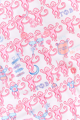 Introducing the Roller Rabbit Gamma Phi Beta Monkey Polo Pajamas: a short-sleeve Pima cotton set featuring a button-up top and matching shorts, adorned with a whimsical pink and blue monkey pattern and red trim on a crisp white background.