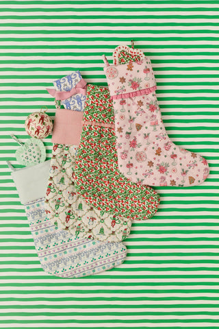 SAPPHIRE Seasons Soiree Quilted Ruffle Stocking in pale pink, featuring a pattern of poinsettias, gingerbread men, and holiday treats, finished with a ruffled trim at the cuff.