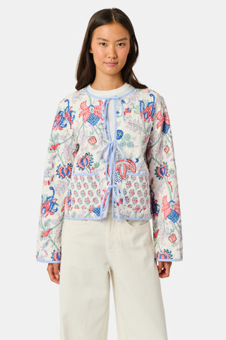 A woman stands facing forward against a plain white background, wearing the Roller Rabbit Amanda Sophie Jacket—a reversible cotton piece featuring blue, red, and pink floral and abstract designs—paired with cream-colored pants.