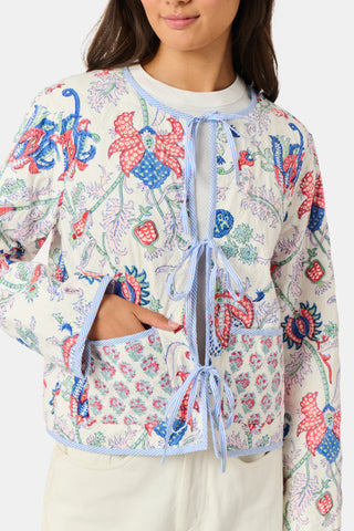 A woman stands facing forward against a plain white background, wearing the Roller Rabbit Amanda Sophie Jacket—a reversible cotton piece featuring blue, red, and pink floral and abstract designs—paired with cream-colored pants.