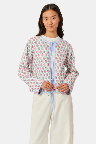 A woman stands facing forward against a plain white background, wearing the Roller Rabbit Amanda Sophie Jacket—a reversible cotton piece featuring blue, red, and pink floral and abstract designs—paired with cream-colored pants.