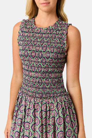 A woman wearing the Roller Rabbit Amelia Emma Dress, featuring a smocked bodice and maxi skirt, stands against a plain white background, paired with green polka-dot flats.
