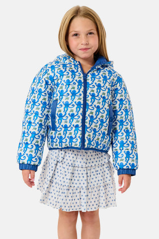 A child wears a blue SOPHISTICA Kids Monkey Reversible Puffer Jacket featuring heart-shaped quilting, a white and light blue chest stripe, and a hood.