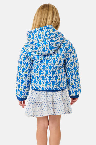 A child wears a blue SOPHISTICA Kids Monkey Reversible Puffer Jacket featuring heart-shaped quilting, a white and light blue chest stripe, and a hood.