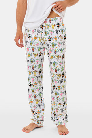 A smiling child in Roller Rabbit’s Kids Boo Crew Pajamas, crafted from soft Pima cotton, sits with arms raised on outdoor steps among women in coordinating patterned pajamas, all sharing a cheerful and relaxed moment together.