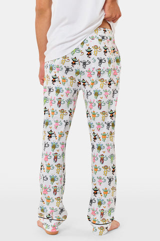 A smiling child in Roller Rabbit’s Kids Boo Crew Pajamas, crafted from soft Pima cotton, sits with arms raised on outdoor steps among women in coordinating patterned pajamas, all sharing a cheerful and relaxed moment together.