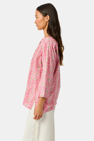 A woman wearing the Roller Rabbit Cora Floral Stripe Pippa Dress—a pink, short-sleeve, midi-length cotton dress with ruffled shoulders and a floral pattern—stands facing forward against a plain white background.