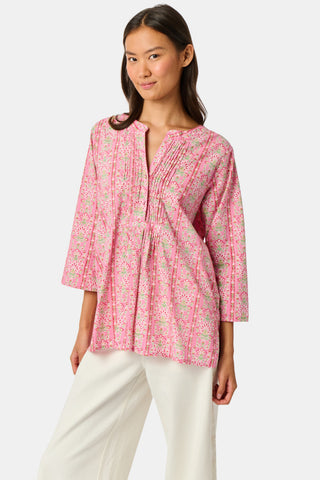 A woman wearing the Roller Rabbit Cora Floral Stripe Pippa Dress—a pink, short-sleeve, midi-length cotton dress with ruffled shoulders and a floral pattern—stands facing forward against a plain white background.