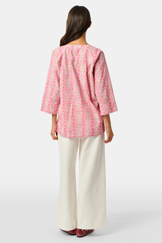 A woman wearing the Roller Rabbit Cora Floral Stripe Pippa Dress—a pink, short-sleeve, midi-length cotton dress with ruffled shoulders and a floral pattern—stands facing forward against a plain white background.