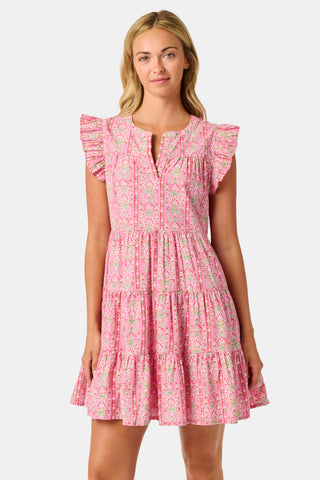 A woman wearing the Roller Rabbit Cora Floral Stripe Pippa Dress—a pink, short-sleeve, midi-length cotton dress with ruffled shoulders and a floral pattern—stands facing forward against a plain white background.