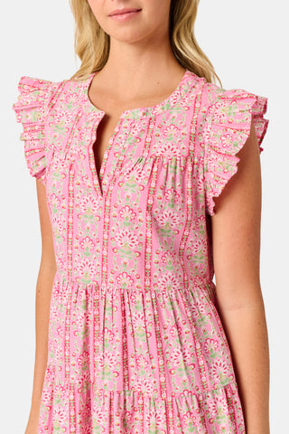 A woman wearing the Roller Rabbit Cora Floral Stripe Pippa Dress—a pink, short-sleeve, midi-length cotton dress with ruffled shoulders and a floral pattern—stands facing forward against a plain white background.