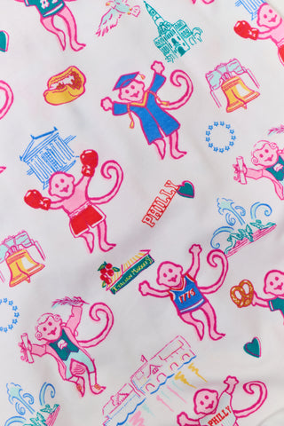 A woman stands barefoot wearing a matching long-sleeve Roller Rabbit Philly Monkey Pajamas set featuring a colorful floral and animal print on a white background.