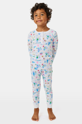 The Kids Game Day Pajamas by Roller Rabbit are a children’s long-sleeve pajama set crafted from soft Pima cotton, featuring a vibrant party-themed print with colorful dinosaurs, bunting, gifts, and party hats on a white background.