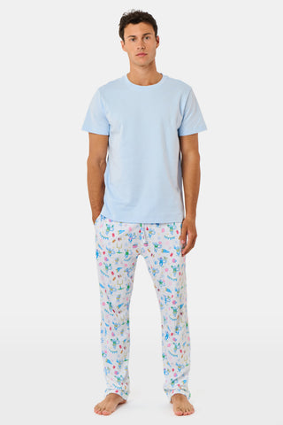 The Mens Game Day Troy Pajamas set by Roller Rabbit features a light blue short-sleeve t-shirt paired with white pajama pants decorated with colorful, playful cartoon animal and toy prints. The set is displayed on a plain white background.