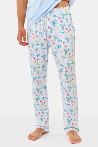 The Mens Game Day Troy Pajamas set by Roller Rabbit features a light blue short-sleeve t-shirt paired with white pajama pants decorated with colorful, playful cartoon animal and toy prints. The set is displayed on a plain white background.
