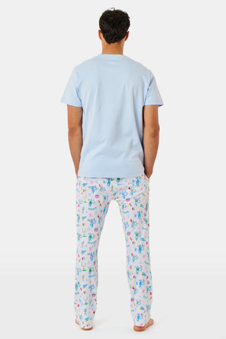 The Mens Game Day Troy Pajamas set by Roller Rabbit features a light blue short-sleeve t-shirt paired with white pajama pants decorated with colorful, playful cartoon animal and toy prints. The set is displayed on a plain white background.