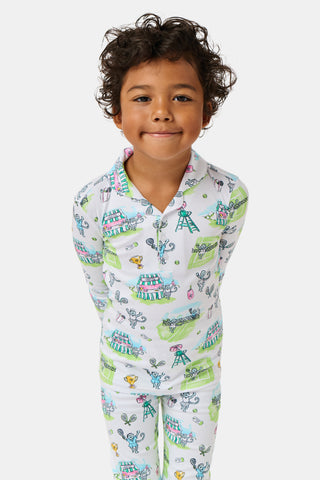 The Roller Rabbit Kids Game, Set, Monkey Parker Polo Pajamas feature a playful print of mice, tents, and trees on a white background. Made from soft pima cotton, this pajama set includes a long-sleeve button-up top and matching pants for children.
