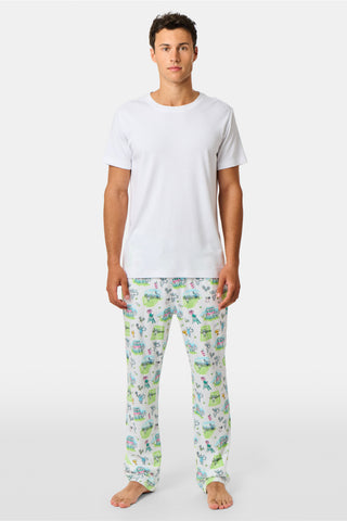 The Roller Rabbit Mens Game, Set, Monkey Troy Pajamas feature a white short-sleeve t-shirt paired with white pajama pants decorated with a vibrant dinosaur and jungle print in green, blue, and black. This playful Pima cotton loungewear set from Roller Rabbit is displayed on a plain white background.