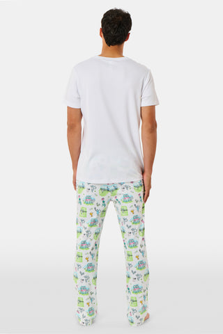 The Roller Rabbit Mens Game, Set, Monkey Troy Pajamas feature a white short-sleeve t-shirt paired with white pajama pants decorated with a vibrant dinosaur and jungle print in green, blue, and black. This playful Pima cotton loungewear set from Roller Rabbit is displayed on a plain white background.