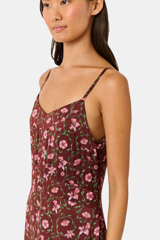 A woman wears a brown silk satin Greta Floral Ditsy Alice Dress with a sweetheart neckline, pink floral ditsy print, and thin straps, paired with brown ankle boots.