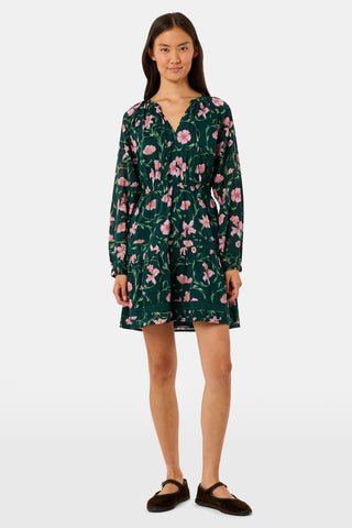 A model wears the SOPHISTICA Greta Floral Belle Dress, a dark green cotton mini dress featuring a pink floral print, a gathered waist, and a ruffled hem.