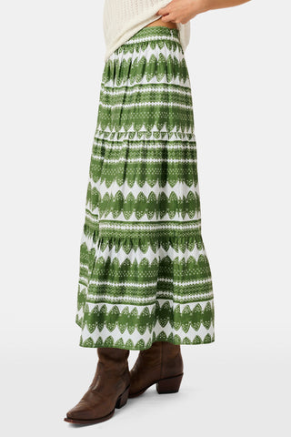 A person wearing the Roller Rabbit Hayam Carlisa Skirt in an olive and white print, paired with a cream knit top and brown boots, stands against a plain white background.