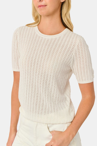 A woman wearing the Roller Rabbit Chain Pointelle Lauren Sweater in cream and white pants, standing against a white background.