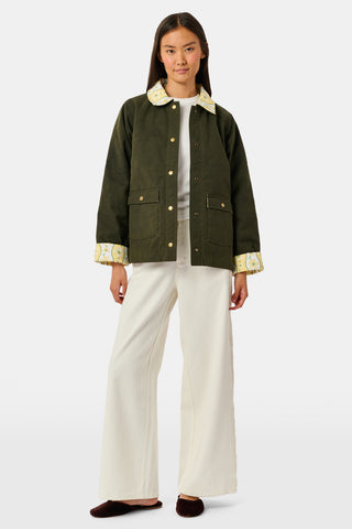 A young girl wearing a Roller Rabbit Kids Lillian Floral Stripe Finn Jacket paired with a matching ruffled skirt and gold ballet flats, standing and smiling against a plain white background—perfect for back-to-school style.