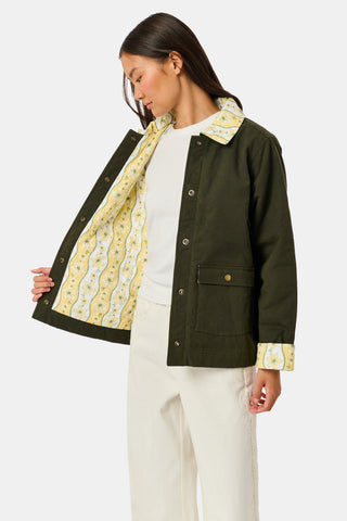 A young girl wearing a Roller Rabbit Kids Lillian Floral Stripe Finn Jacket paired with a matching ruffled skirt and gold ballet flats, standing and smiling against a plain white background—perfect for back-to-school style.