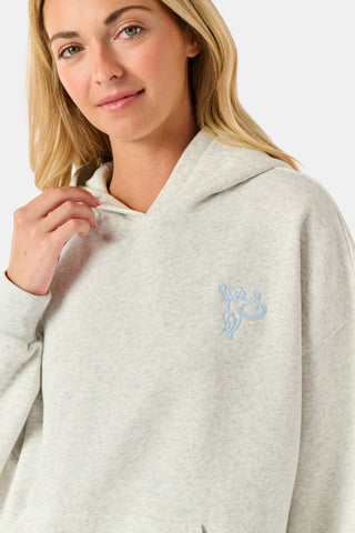 A person is wearing the Roller Rabbit Sleep Club Mimi Sweatpants in light gray, featuring wide legs and crafted from velvety soft Dream Fleece with “Sleep Club” printed in light blue on the left thigh, paired with white sneakers and a cropped white top. The background is plain white.