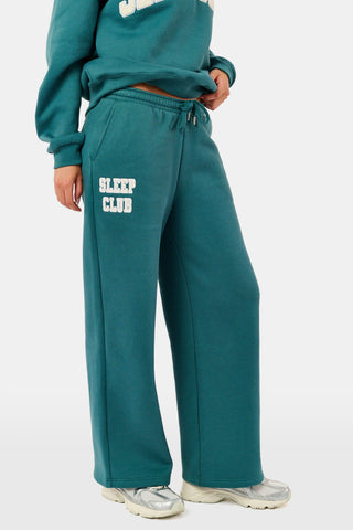 Deep teal wide-leg Sleep Club Mimi Sweatpants in Dream Fleece with an elastic drawstring waist and SLEEP CLUB printed on the right hip.