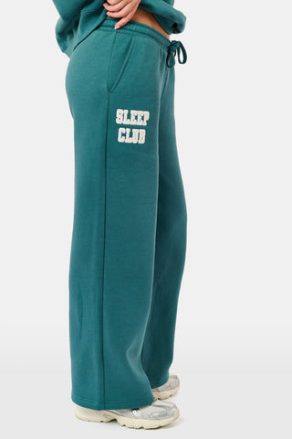 Deep teal wide-leg Sleep Club Mimi Sweatpants in Dream Fleece with an elastic drawstring waist and SLEEP CLUB printed on the right hip.