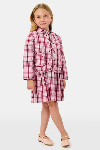 A young girl wearing a pink and white plaid hearts Kids Plaid Hearts Finn Jacket and a matching skirt.