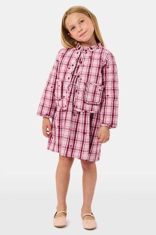 A young girl wearing a pink and white plaid hearts Kids Plaid Hearts Finn Jacket and a matching skirt.