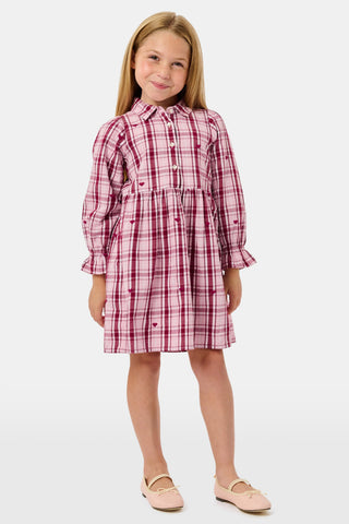 A girl wears a pink and white plaid hearts SAPPHIRE Kids Plaid Hearts Isabelle Dress with long sleeves and light-colored ballet flats.