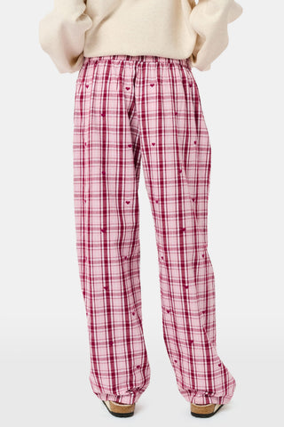 A woman wearing a SAPPHIRE Plaid Hearts Perlita Night Shirt in a pink and maroon plaid pattern with small hearts.