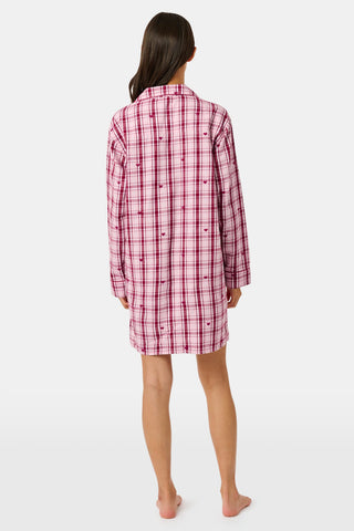 A woman wearing a SAPPHIRE Plaid Hearts Perlita Night Shirt in a pink and maroon plaid pattern with small hearts.