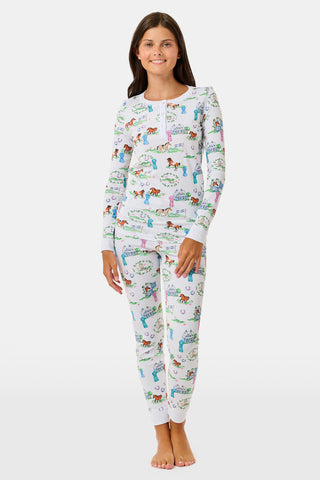 Introducing the Kids Saddle Up Pajamas by Roller Rabbit—a children’s pajama set crafted from premium Pima cotton, featuring a whimsical equestrian print of horses, castles, and greenery on a white background. This high-quality set includes a long-sleeve top and matching pants.
