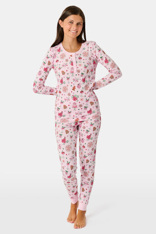A child in a patterned Kids Seasons Soiree Juniper Pajamas two-piece set and rubber boots sits on a wooden sled and looks through binoculars.