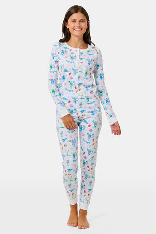 The Kids Game Day Pajamas by Roller Rabbit are a children’s long-sleeve pajama set crafted from soft Pima cotton, featuring a vibrant party-themed print with colorful dinosaurs, bunting, gifts, and party hats on a white background.